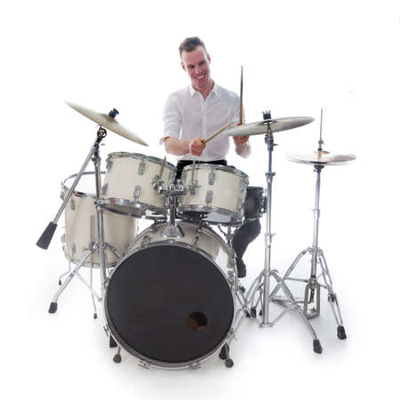 white drummer behind drum set wears white shirt and plays the drums in studio smilingの写真素材
