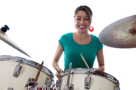 brunette brazilian woman has fun playing the drums in studio against white backgroundの写真素材