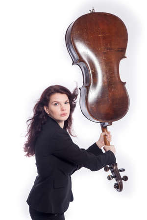 beautiful brunette woman uses cello as quirky baseball bat in studio against white backgroundの写真素材