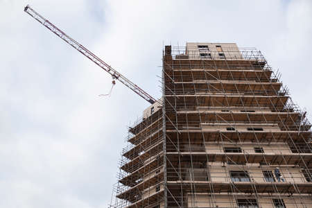 scaffolding on building site of new apartment building and crane against skyの写真素材