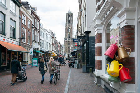 people shop in zadelstraat of city utrecht in holland with Dom tower behindのeditorial素材