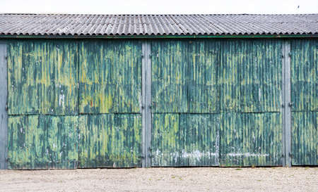 horizontal picture of rusty corrugated iron doors of shed with green yellow paintの写真素材