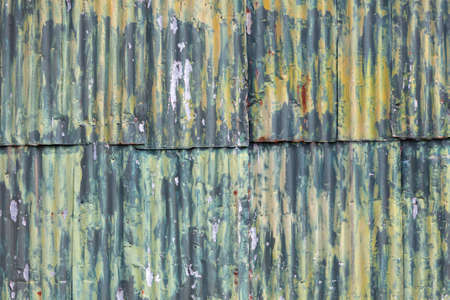 horizontal picture of rusty corrugated iron wall of she with green yellow paintの写真素材