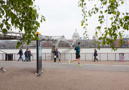 London, United Kingdom, 6 may 2017: people walk and jog near millennium bridge along river thames in london on overcast day in springのeditorial素材