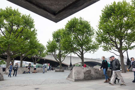 London, United Kingdom, 6 may 2017: people on southbank of river thames in front of national theatre near waterloo bridge on overcast day in springのeditorial素材