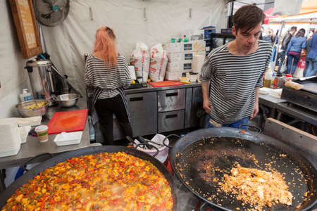 London, United Kingdom, 6 may 2017: vendors of stall with colorful dish on southbank centre food market in londonのeditorial素材