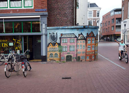 bicycles and painted houses in the centre of old capital Leeuwarden of province of friesland in the netherlands with boy on bike passingのeditorial素材
