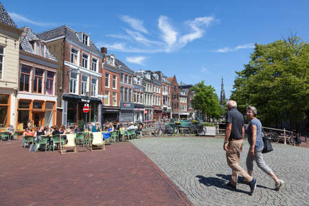 leeuwarden, 11 june 2017: older couple walks towards outdoor cafe on bridge in the centre of old city leeuwarden in friesland on sunny summer dayのeditorial素材
