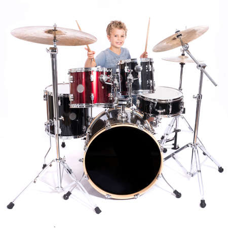 young blond caucasian boy plays drums in studio against white backgroundの写真素材