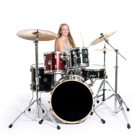 young blond caucasian teenage girl plays the drums in studio against white backgroundの写真素材