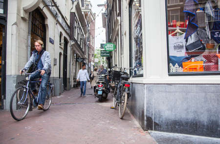 people and bikes near souvenir shop in centre of amsterdam in hollandのeditorial素材