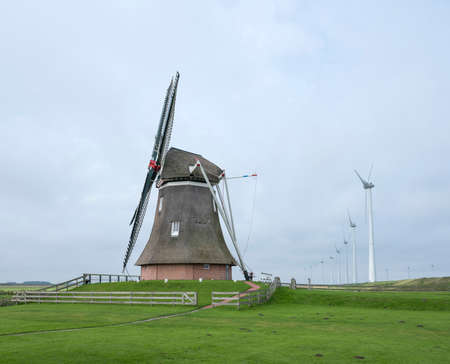 old windmill goliath at roodeschool in the dutch province of groningen between row of modern wind turbinesの写真素材
