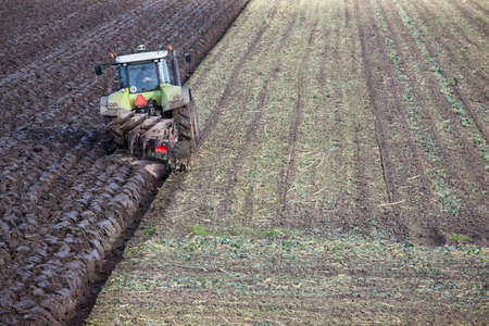 tractor and plow at work on field in the dutch province of flevoland in the netherlandsの写真素材
