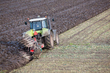 tractor and plow at work on field in the dutch province of flevoland in the netherlandsの写真素材