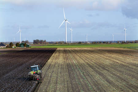 tractor and plow at work on field in the dutch province of flevoland in the netherlandsの写真素材