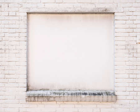 white painted brick wall with blind window of old building
