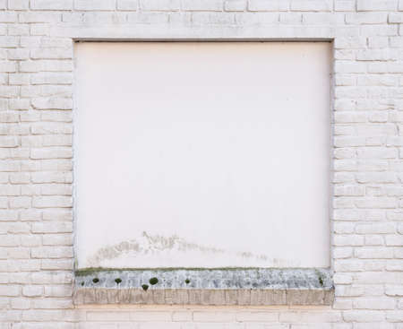 white painted brick wall with blind window of old buildingの写真素材