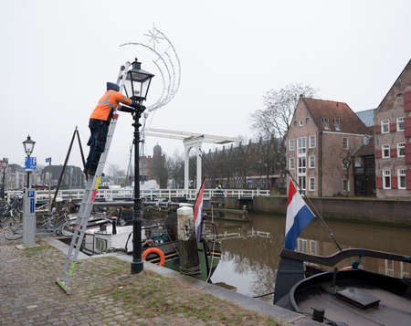 man applies christmas decoration in the old town of zwolle in the netherlandsのeditorial素材