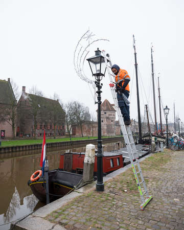 man applies christmas decoration in the old town of zwolle in the netherlandsのeditorial素材