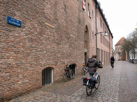 woman on bicycle in old city of zwolle in the netherlands near ancient town wallのeditorial素材