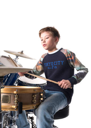 young blond boy at drum kit in studio against white backgroundの写真素材