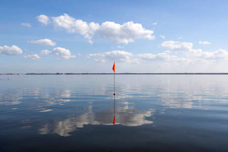 orange red flag floating in water as marker for shallow waterの写真素材