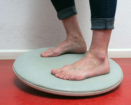 closeup of feet under blue jeans on balance board on red floorの写真素材