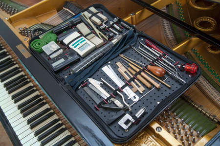 closeup of hand and tools of tuner working on grand piano