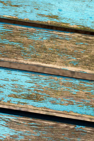 closeup of old grungy bench planks with peeling blue paintの写真素材
