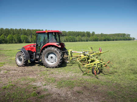 Meerkerk, Netherlands, 9 may 2018: tractor and grass turner work in dutch meadow in the province of south holland in the netherlands on sunny dayのeditorial素材
