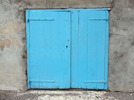 old blue painted closed doors in wall of house in french provenceの写真素材