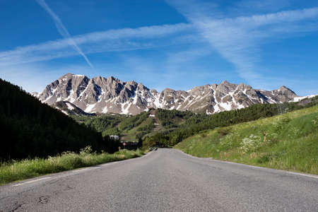 road and snow capped mountains in parc mercantour neaqr col de vars in the french provence with blue...