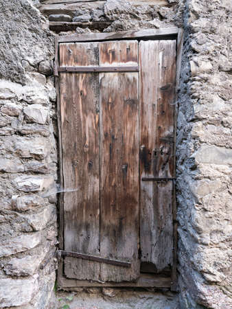 very old brown grungy door in ancient wall of medieval house in village of french provenceの写真素材