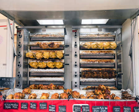 whole golden brown chickens on grill for sale on market in french town of besancon
