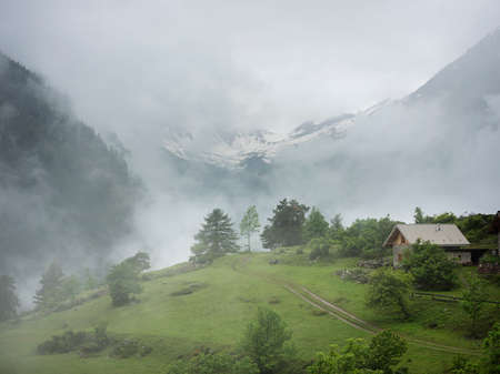house high up in the mountains of national park des ecrins in haute provence on rainy cloudy summer day with mountains and clouds in the backgroundの写真素材