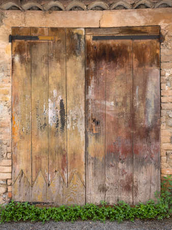 very old weathered brown doors in ancient wall of medieval village in french provenceの写真素材