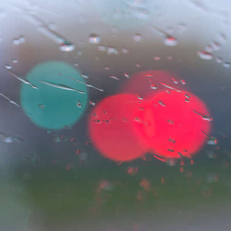 abstract pattern of colorful lights and rain drops during downpour on winshield of car after darkの写真素材