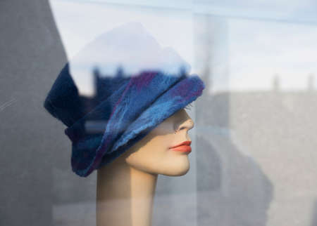 female dummy with blue woolen hat in display window and reflectionsの写真素材