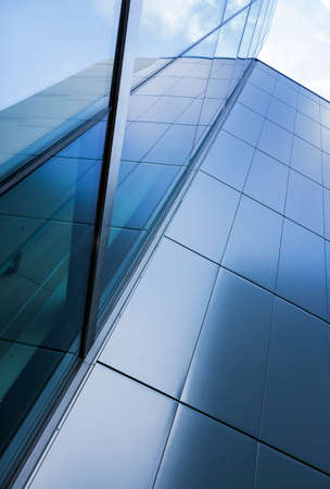 detail of modern corporate office building with glass and steel reflecting blue sky and clouds