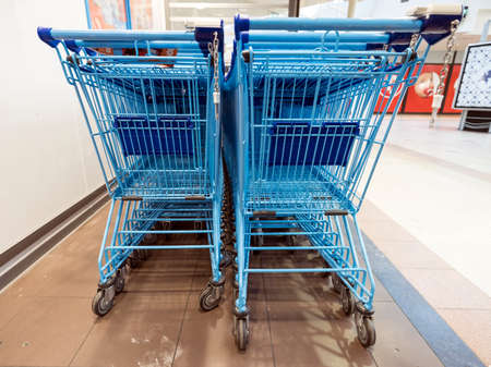 blue shopping carts wait outside supermarket for customersの写真素材