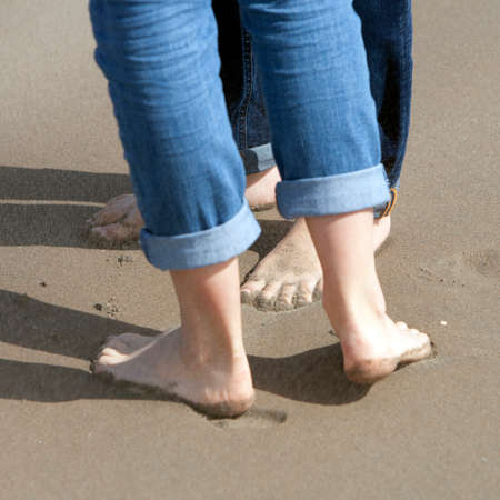 two pairs of feet close together on sand of beach of couple kissingの写真素材