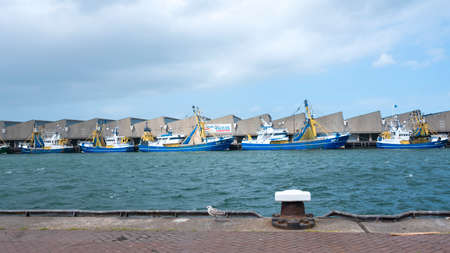 blue fishing boats lie in scheveningen harbor on stormy summer day in the netherlandsの写真素材