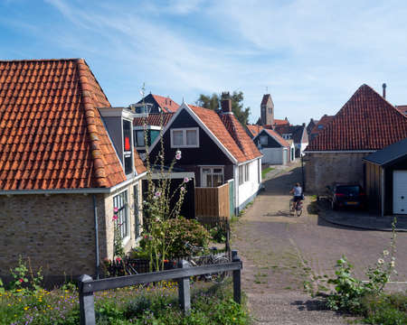 makkum, netherlands, 23 august 2019: old village of makkum with woman on bicycle between old small housesのeditorial素材