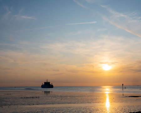 ferry from ameland arrives on waddenzee during sunset at harbour of Holwerd in dutch province of frieslandの写真素材