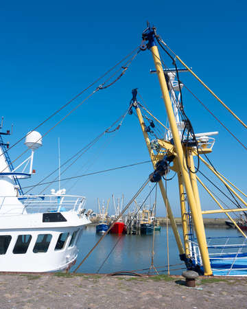 fishing boats in harbor of lauwersoog in the north of groningen in the netherlands on sunny summer day under blue skyの写真素材