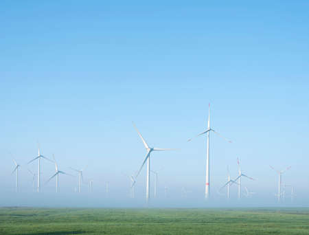 wind turbines in green meadow near aurich in german lower saxony on misty morning in augustの写真素材