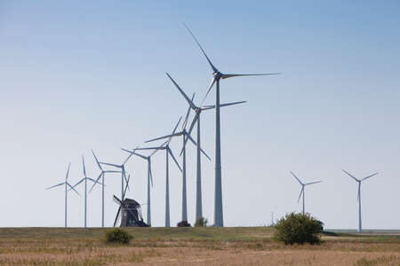 old dutch windmill and modern wind turbines against blue sky in dutch province of groningen near...