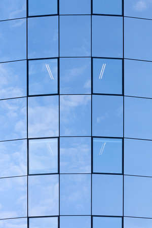 part of glass facade on modern office building reflecting blue sky