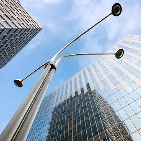 modern office architecture with glass and steel and lamp post under blue sky and cloudsの写真素材