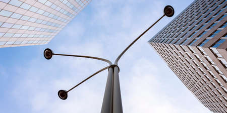 modern office architecture with glass and steel and lamp post under blue sky and cloudsの写真素材